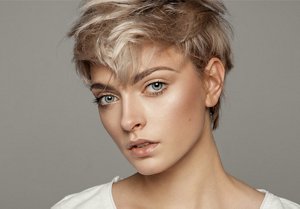 Young woman with a triangular face shape wearing a pixie haircut
